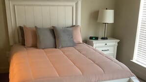 Een netjes opgemaakt bed met een wit hoofdbord en een roze deken.