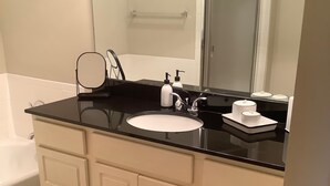 Een moderne badkamer met een zwart aanrecht, een witte wastafel en een grote spiegel.