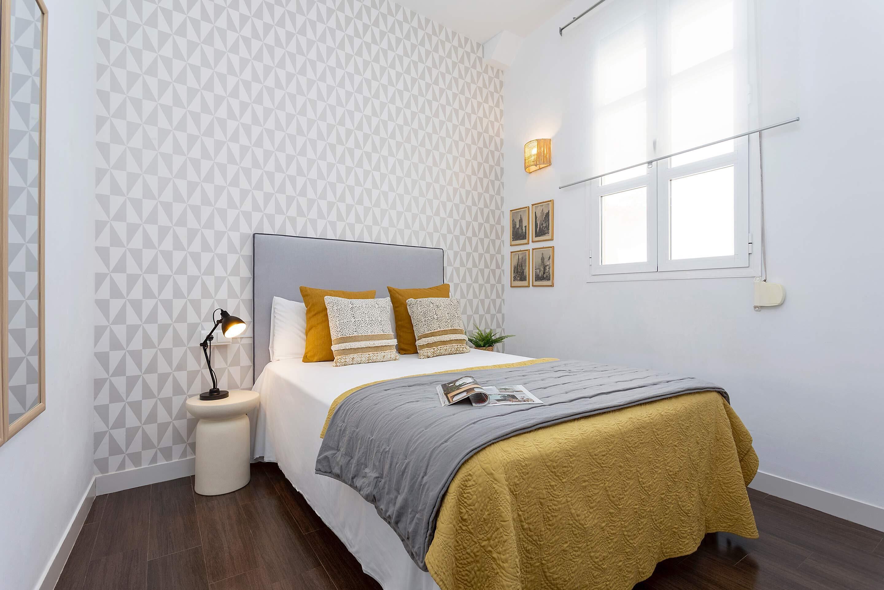 Une chambre à coucher avec un lit, une lampe de chevet et une fenêtre.