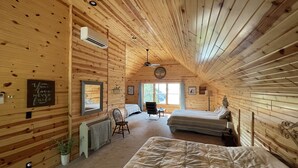 Une cabane confortable avec deux lits, un ventilateur de plafond et des murs en bois.