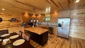 Une cuisine moderne avec un revêtement mural en bois, des appareils électroménagers en acier inoxydable et un îlot central doté de sièges.