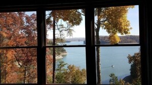 Une vue à travers une fenêtre sur un lac et le feuillage d’automne.