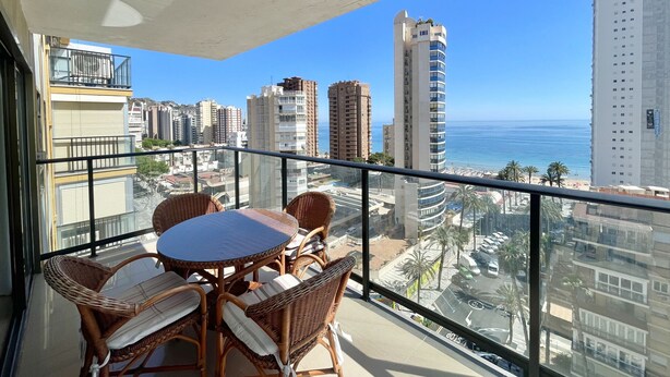 Ein Balkon mit Korbmöbeln und Blick auf Stadt und Meer.