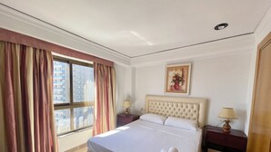 Ein Hotelzimmer mit einem großen Bett, einem Fenster mit Vorhängen, einem Nachttisch mit Lampe und einem Gemälde an der Wand.