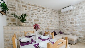 Un'area pranzo con una parete in pietra, un divano e un tavolo apparecchiato per quattro, con piatti, bicchieri e posate.