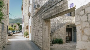 Una stretta via con edifici in pietra, un numero 22 ben visibile e una piccola zona con tavolini all'aperto.