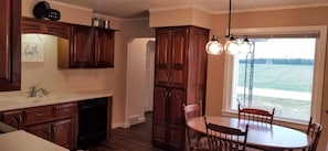 Enjoy meals in the kitchen and dining area with a view of the surrounding grassy field.