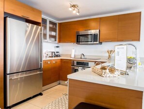 Welcome to our kitchen, equipped with a refrigerator, microwave, and wooden cabinets.