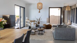 A modern living room with a wooden dining table, grey sofa, and a TV. - VILLA BELLA - 4 bedrooms, heated swimming pool, panoramic sea view (Grosseto-Prugna)