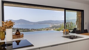A kitchen with a large window overlooking a coastal landscape. - VILLA BELLA - 4 bedrooms, heated swimming pool, panoramic sea view (Grosseto-Prugna)