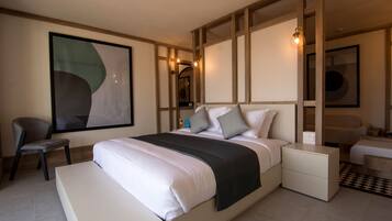 A modern hotel room with a large bed, bedside tables, a chair, and artwork on the walls.