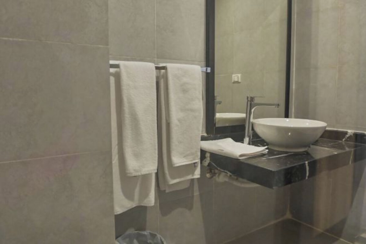 A bathroom with a large mirror, a white sink, and two towels hanging on a rack.