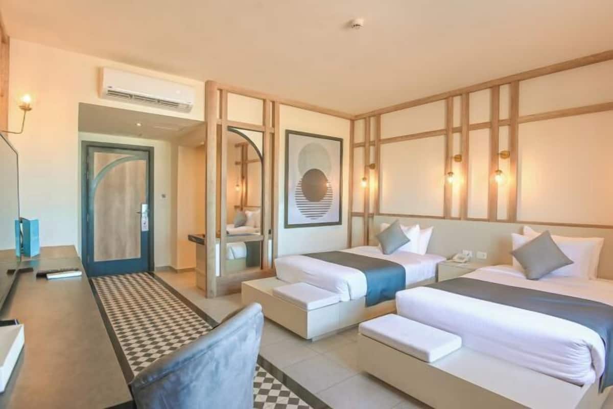 Una habitación de hotel con dos camas, un escritorio, una silla y un espejo.