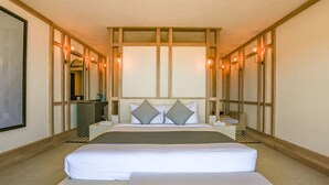 Une chambre d’hôtel avec un grand lit, des tables de chevet, un bureau et un miroir.