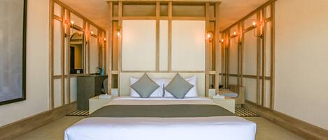 Una habitación de hotel con una cama grande, mesitas de noche, un escritorio y un espejo.