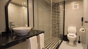 A modern bathroom with a large sink, mirror, and a shower with a checkered tile pattern.