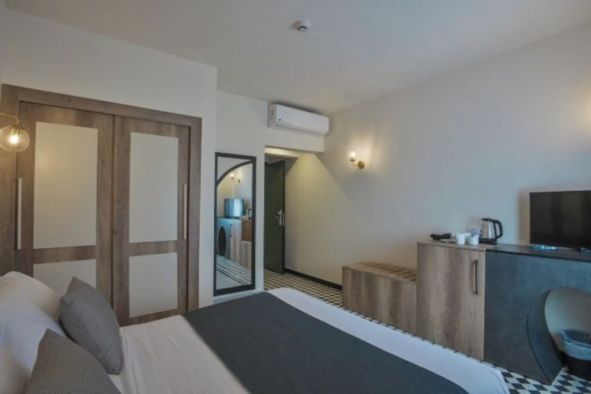 Une chambre d’hôtel comprenant un lit, un bureau avec une chaise, un miroir et un téléviseur.