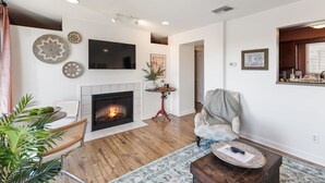 A living room with a fireplace, a flat-screen TV, and a comfortable seating area. - Downtown Condo with River View (Nashville)