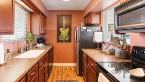A kitchen with wooden cabinets, a stainless steel refrigerator, a granite countertop, and a backsplash. - Downtown Condo with River View (Nashville)