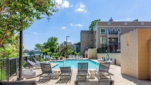 A rooftop pool area with lounge chairs and a view of the city skyline. - Downtown Condo with River View (Nashville)