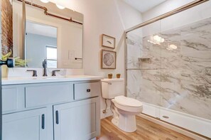 Un baño con tocador blanco, inodoro y cabina de ducha de vidrio.