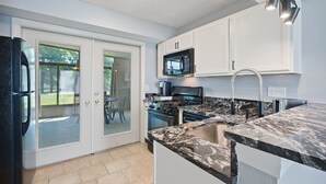 A modern kitchen with white cabinets, a black refrigerator, a microwave, and a gas stove. - Adorable 3 bed, 1.5 bath Ranch Home with fenced yard (Columbus)