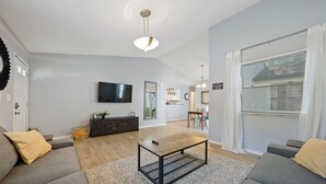 A modern living room with a sofa, coffee table, and a flat-screen TV mounted on the wall. - Adorable 3 bed, 1.5 bath Ranch Home with fenced yard (Columbus)