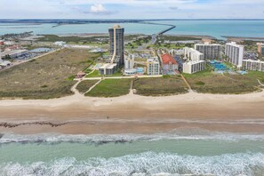 A coastal resort with beachfront properties, a marina, and a prominent pier extending into the water.