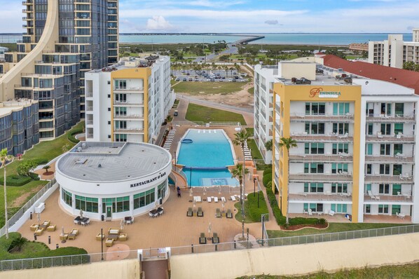A hotel with a pool, outdoor seating, and a view of the beach and ocean.
