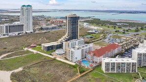 Un complejo hotelero frente al mar con varias edificaciones, incluyendo una torre alta y un edificio circular con piscina.