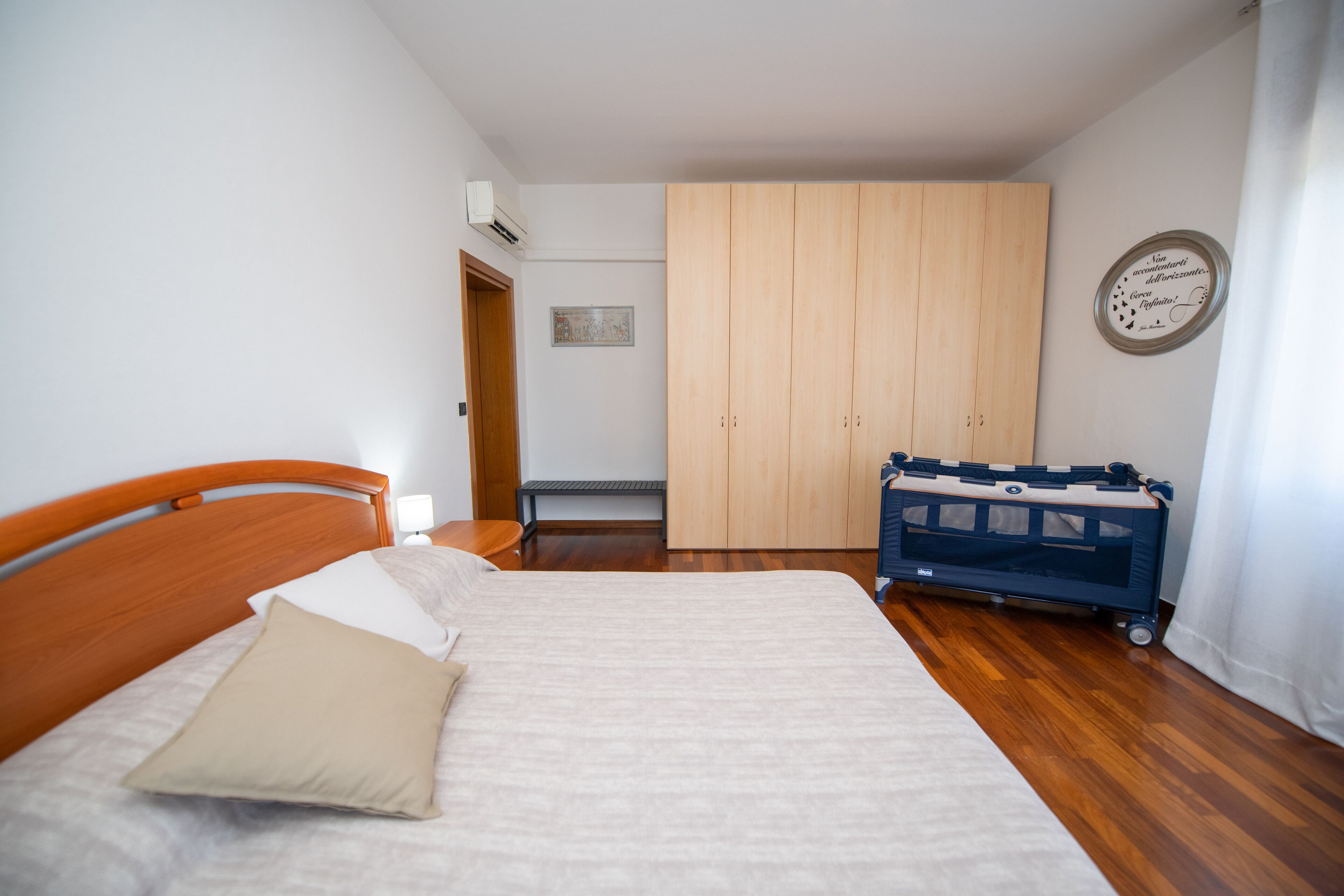 A bedroom with a wooden bed, a bench, a wardrobe, and a crib.