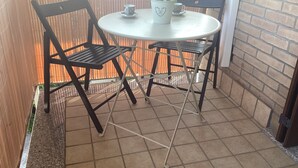 A small outdoor patio with a round table and two chairs. There is a potted plant on the table. - Peter's nest (Verano Brianza)