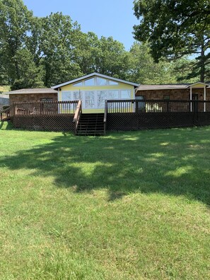A fenced yard with a small building, a wooden staircase, and a grassy area. - Waterfront Home with private boat ramp and boat dock. (Grove)