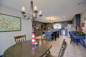 A modern kitchen with a central island, pendant lighting, and a dining area with a round table and chairs. - Waterfront Home with private boat ramp and boat dock. (Grove)