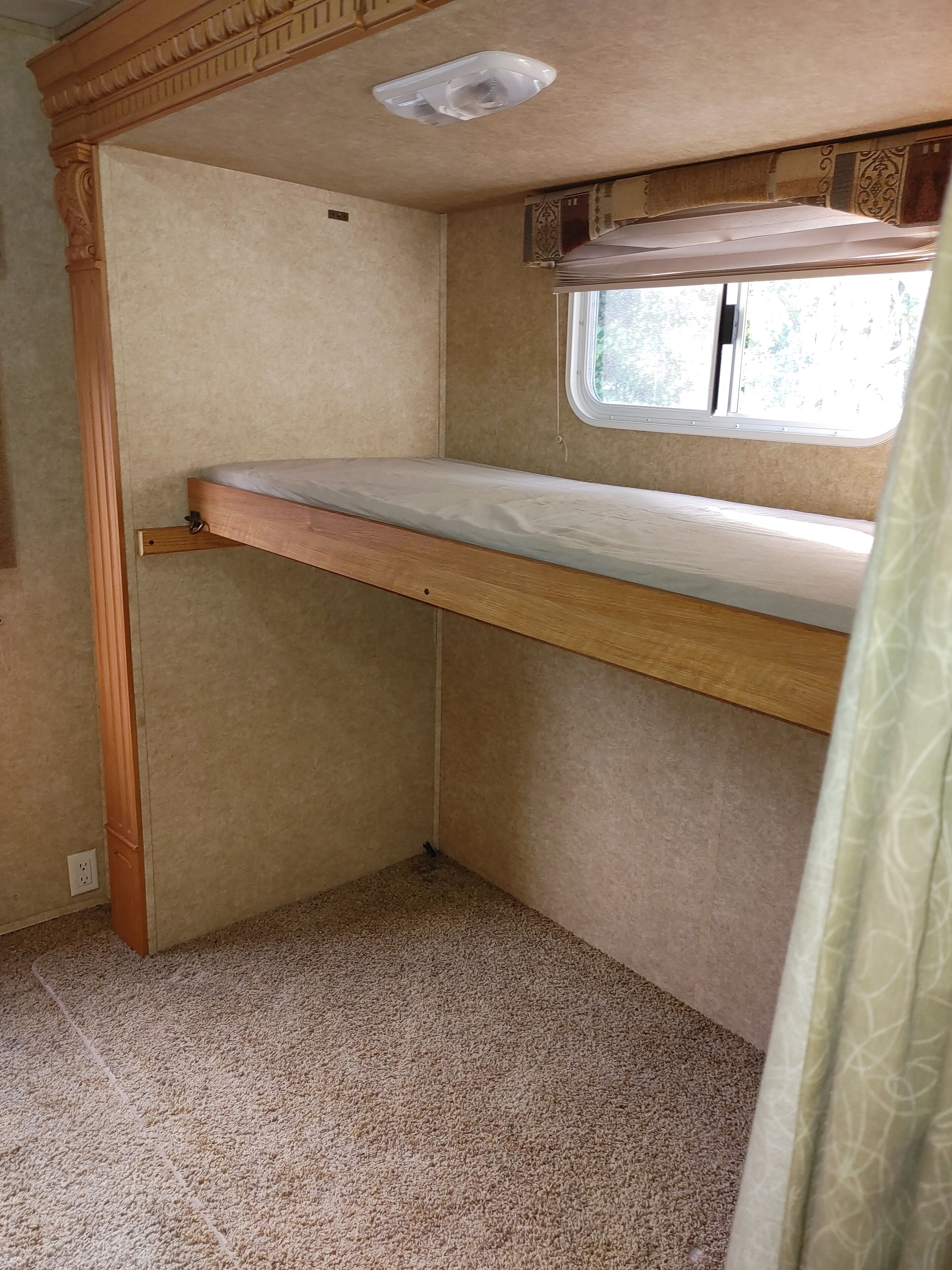 Interior compacto de una autocaravana con literas, una ventana y un respiradero en el techo.