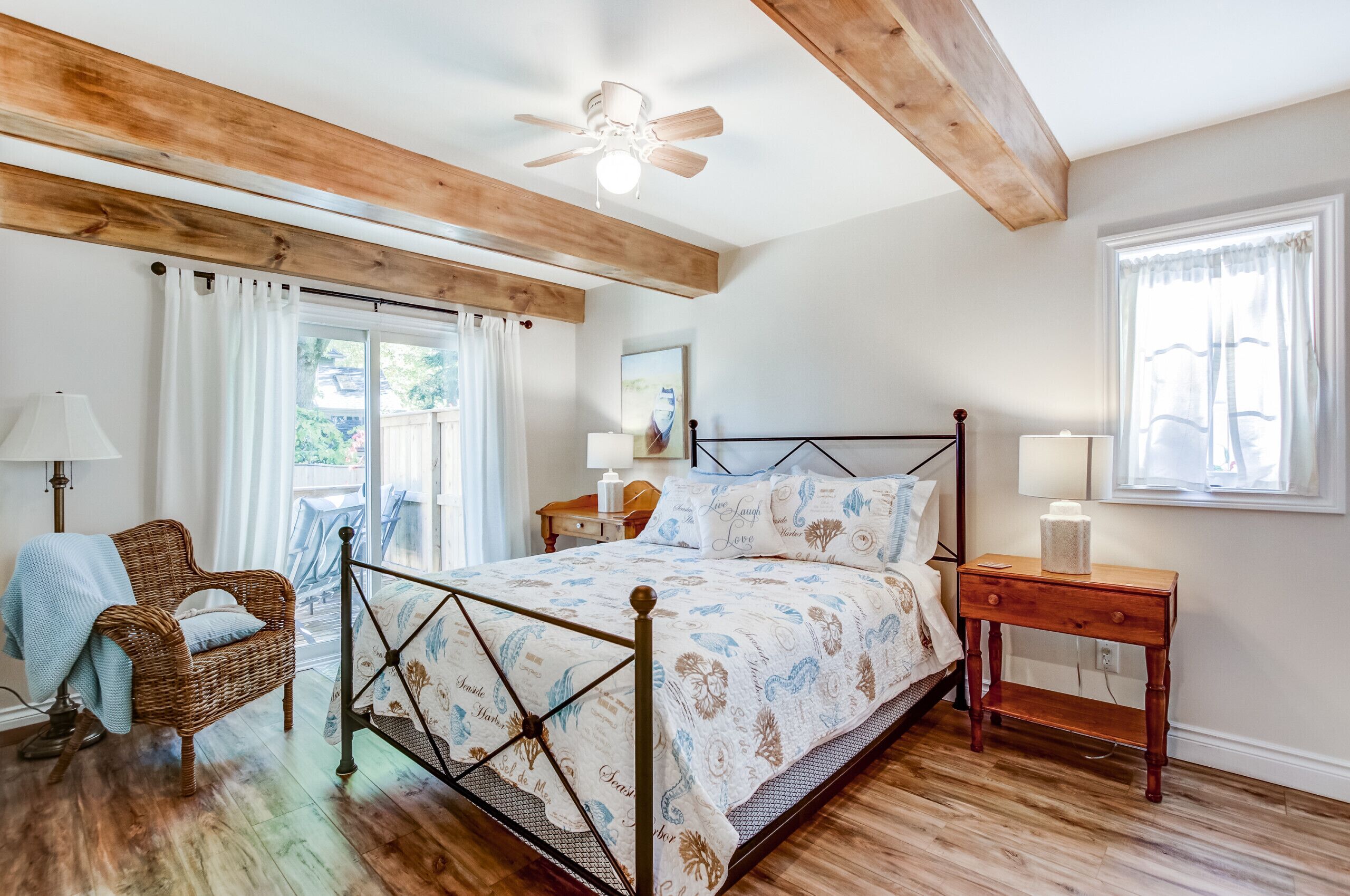 A bedroom with a bed, a chair, a nightstand, a window, and a ceiling fan.