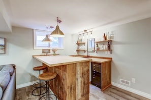 A kitchen with a wooden island, bar stools, pendant lighting, and a built-in dishwasher. - Blue Pearl, Your Tranquil Oasis (Niagara-on-the-Lake)