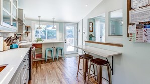 A modern kitchen with white cabinets, a wooden countertop, and a bar area with stools. - Blue Pearl, Your Tranquil Oasis (Niagara-on-the-Lake)
