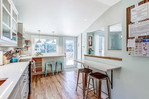 A modern kitchen with white cabinets, a large window, and a bar area with stools. - Blue Pearl, Your Tranquil Oasis (Niagara-on-the-Lake)