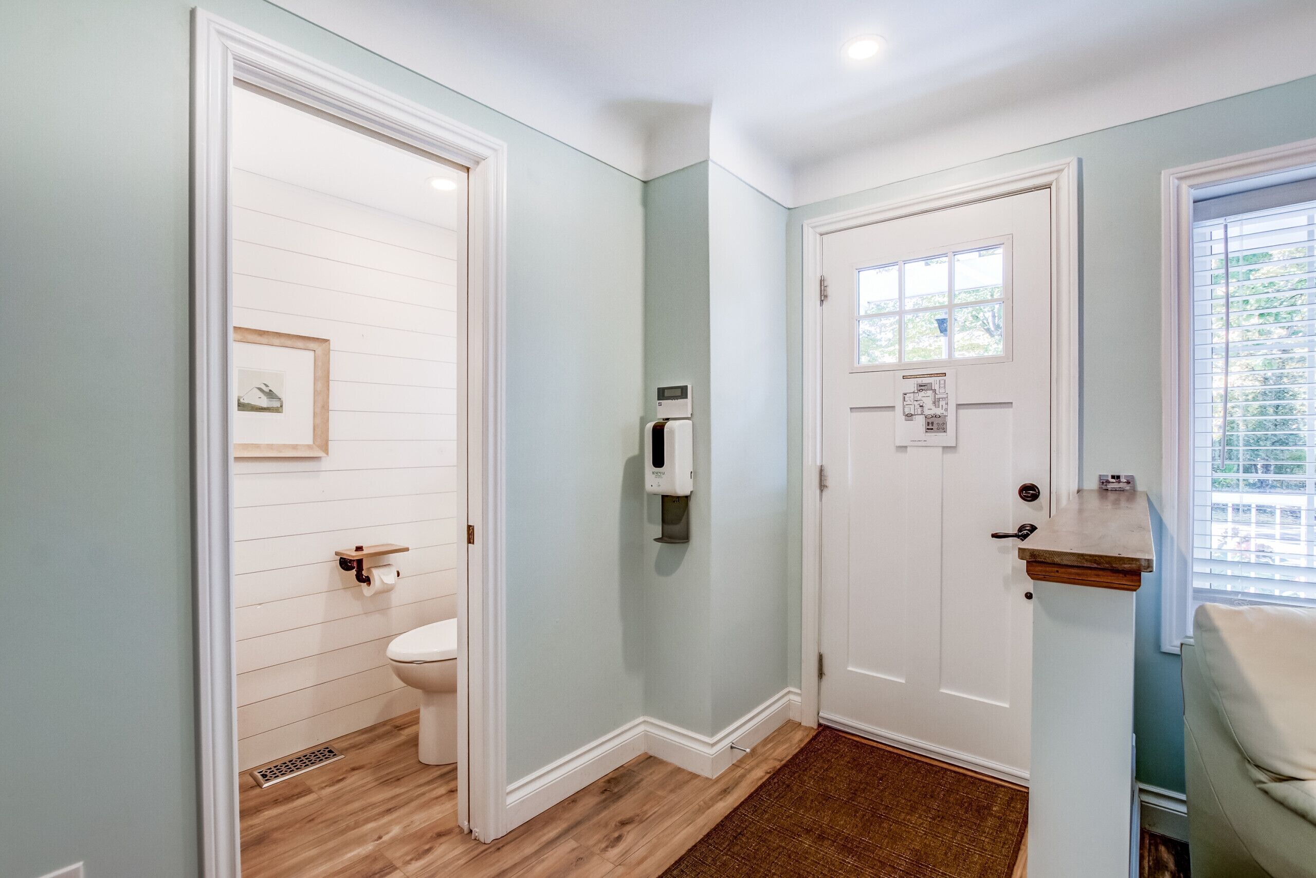 A bathroom with a toilet, a hand dryer, and a small shelf.