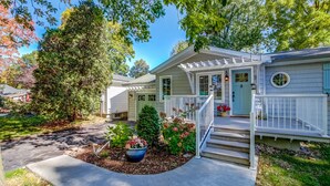 A two-story house with a front porch, a covered entryway, and a small front yard with a potted plant and flowers. - Blue Pearl, Your Tranquil Oasis (Niagara-on-the-Lake)