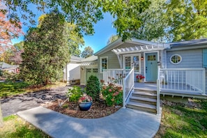 A two-story house with a front porch, a covered entryway, and a small garden with potted plants and flowers. - Blue Pearl, Your Tranquil Oasis (Niagara-on-the-Lake)