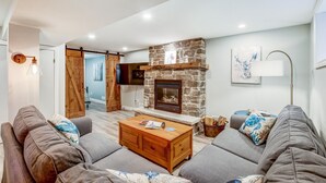 A living room with a stone fireplace, a wooden coffee table, and grey sofas. - Blue Pearl, Your Tranquil Oasis (Niagara-on-the-Lake)