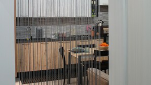 A modern kitchen with a wooden countertop, a sink, and a dining area with a chair and table. - Suite Torre Pali (Trapani)