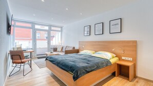 A modern bedroom with a large bed, bedside tables, a desk, and a chair.