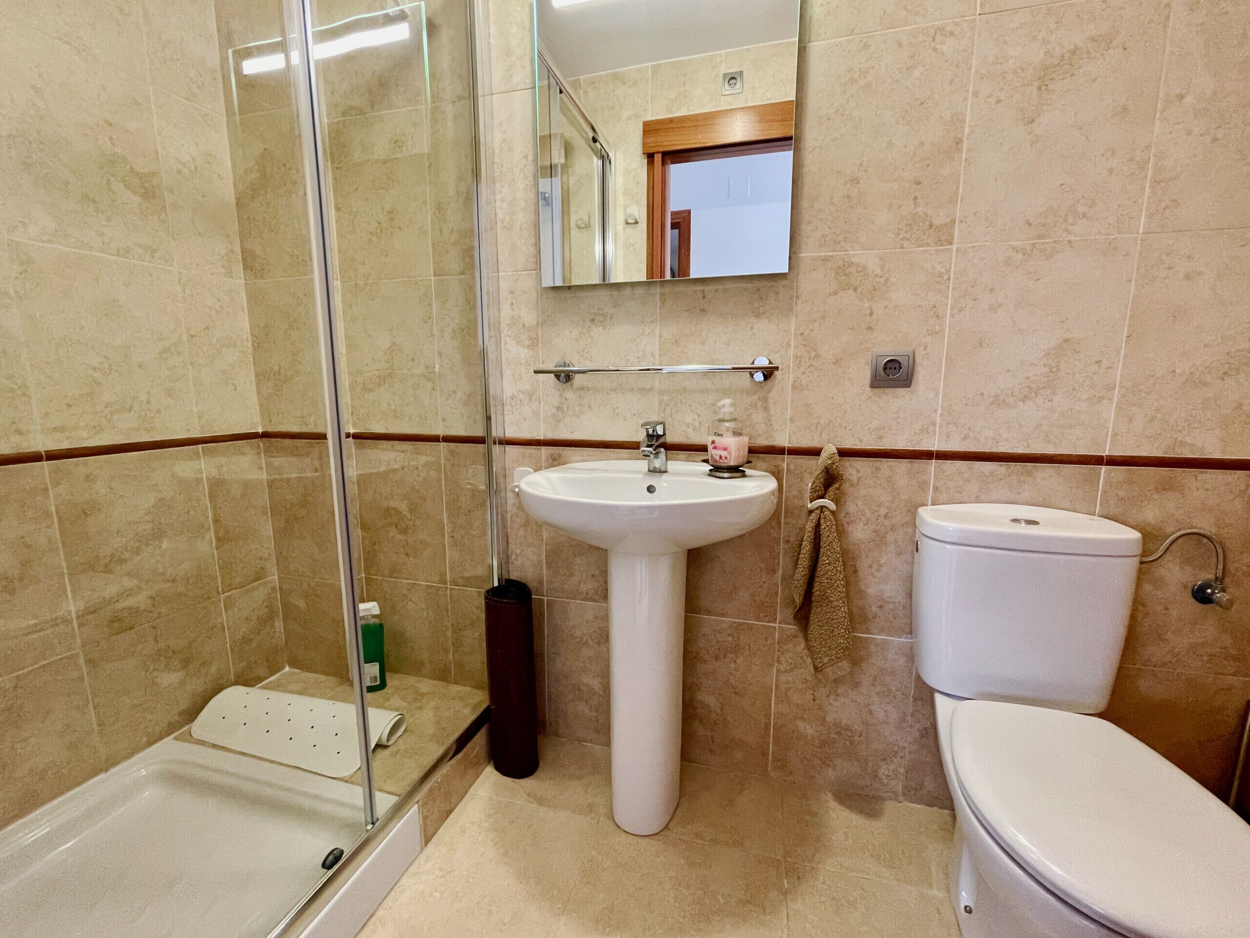 Un baño con ducha, lavamanos e inodoro.