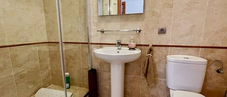 Un baño con ducha, lavamanos e inodoro.