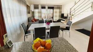 A modern dining area with a granite countertop, a bowl of oranges, and a dining table with chairs. - CASA DANI (Ampolla)