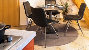 Un comedor con una mesa redonda, sillas negras y una planta en maceta.