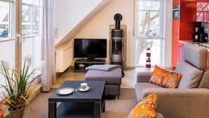 Una sala moderna con televisor, chimenea y muebles de cocina rojos.